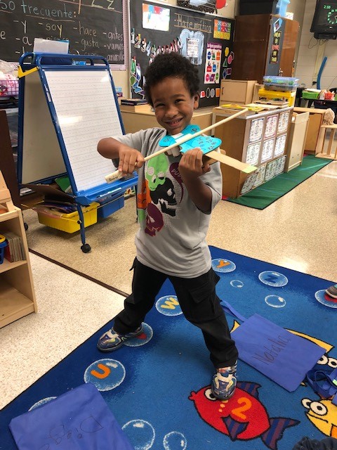 A child holding a cardboard paper violin