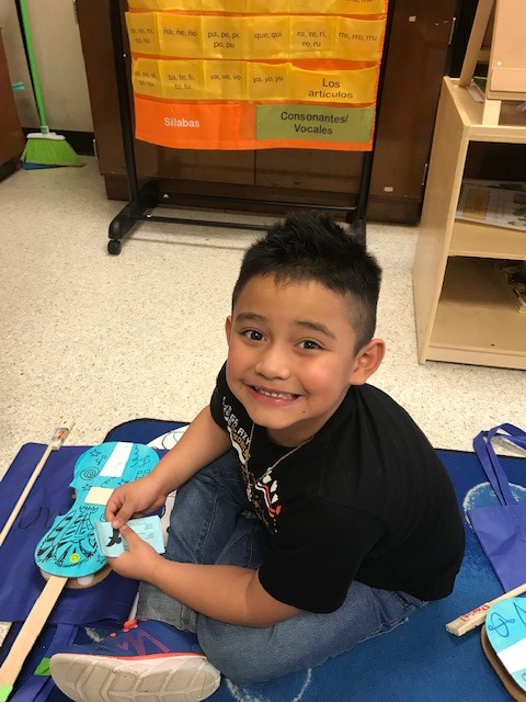 A child holding a cardboard paper violin