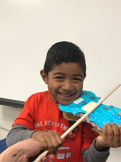 A child holding a cardboard paper violin