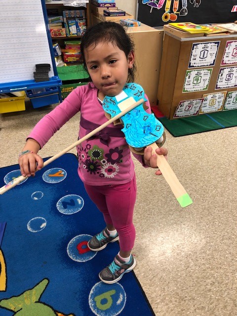 A child holding a cardboard paper violin