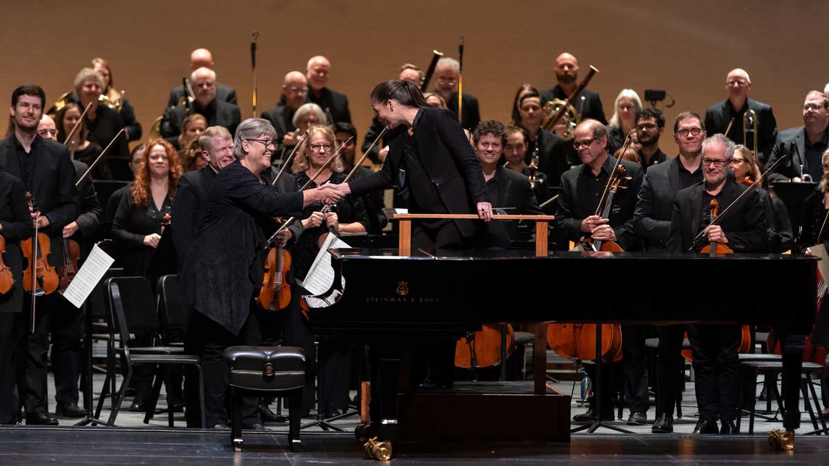 Concertmaster Corine Brouwer and music director Michelle Merrill shake hands during a full-orchestra bow at the end of a performance.