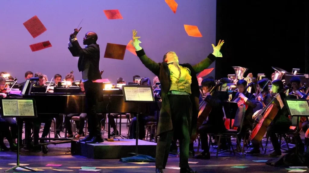 "Beethoven" throws his manuscripts into the air in front of an orchestra